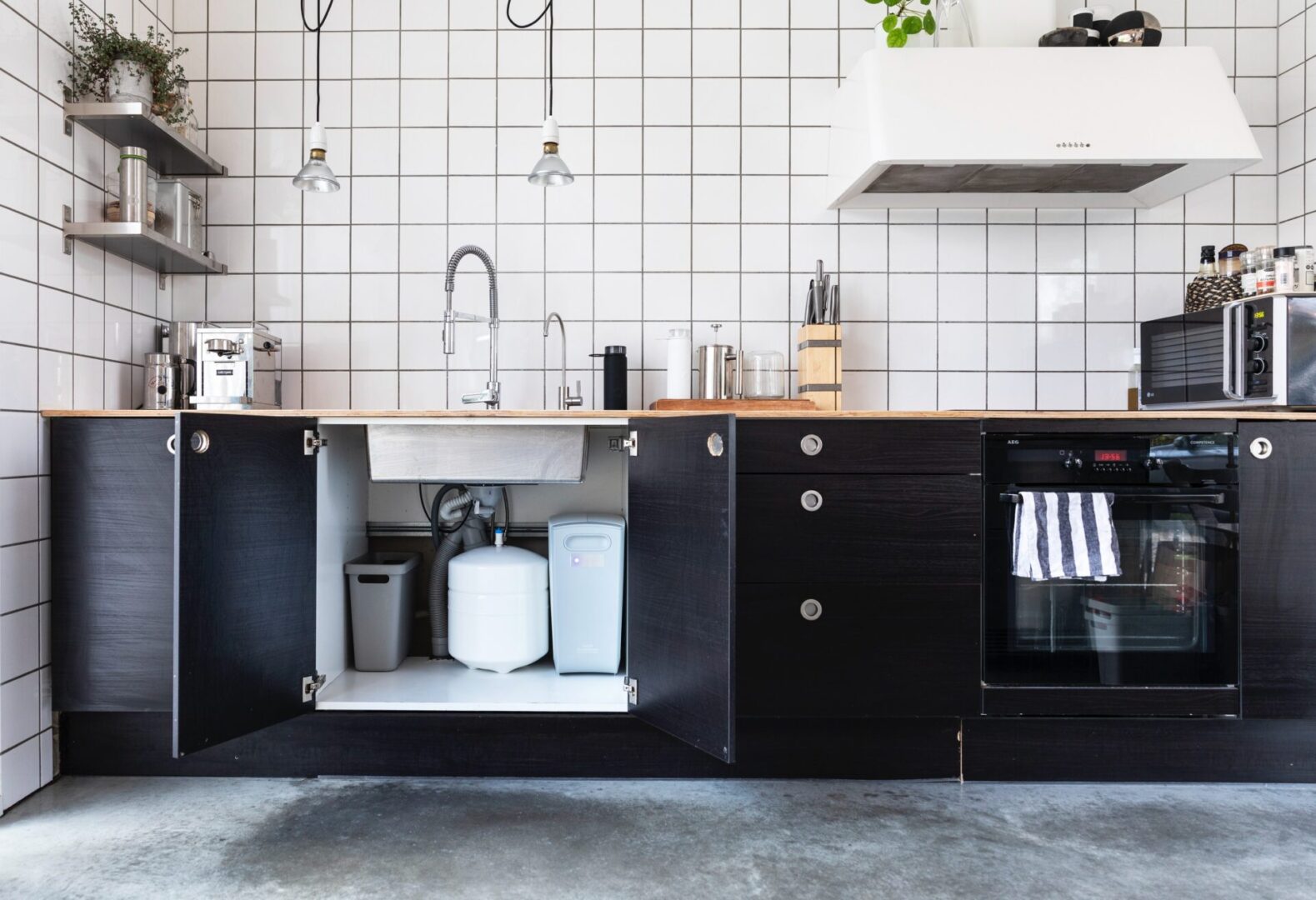 A kitchen with black cabinets and white tile walls.