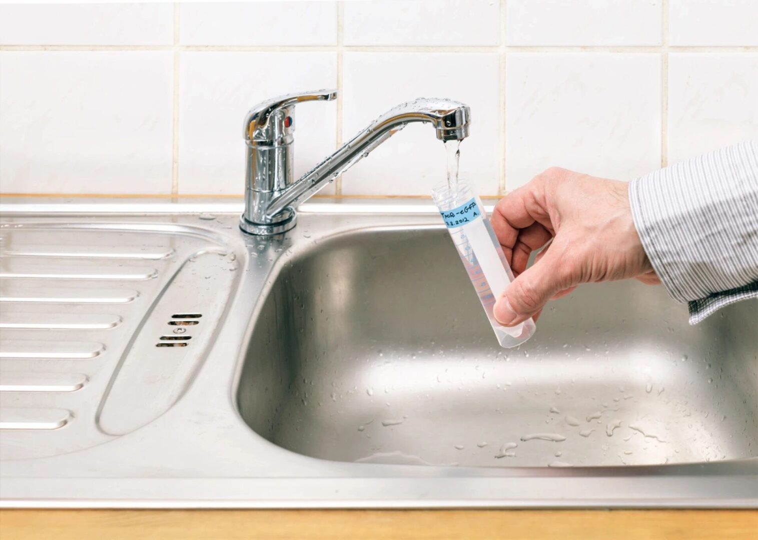 A person is filling up a glass bottle with water.