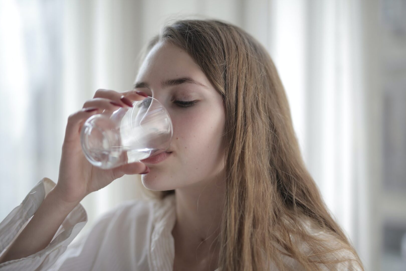 A woman drinking water from a glass.